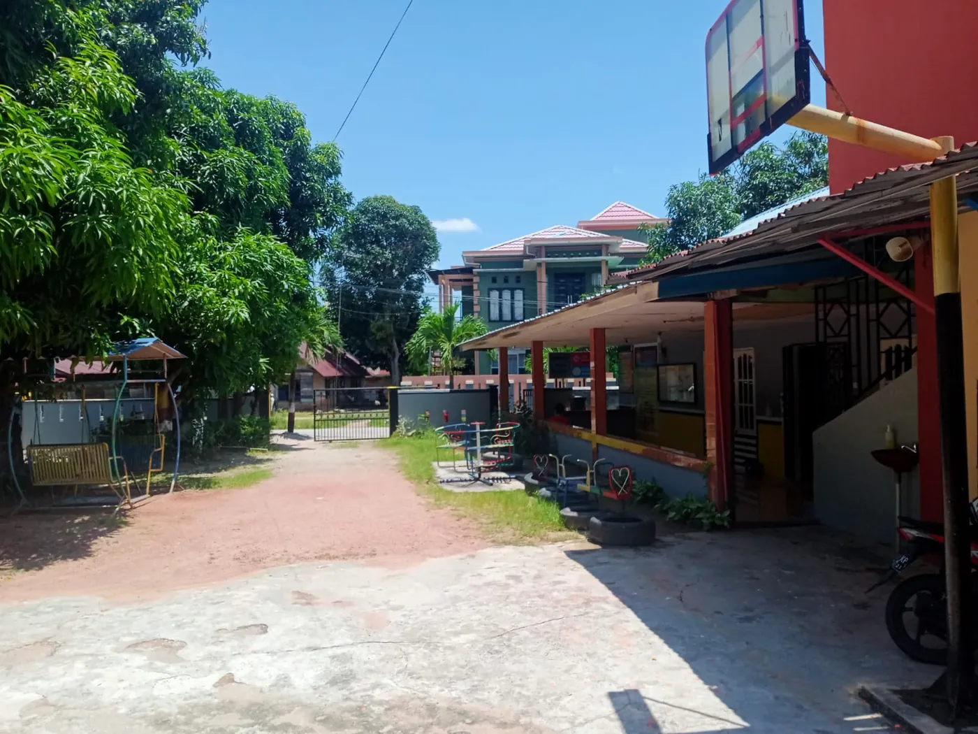Halaman sekolah yang luas dengan ayunan dan tempat bermain
