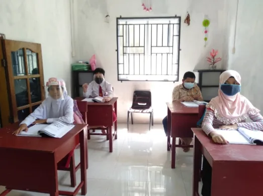 Siswa belajar di kelas, duduk di meja masing-masing bersama guru